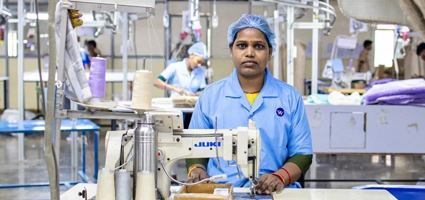 Workers operating sewing machines in a garment factory in India